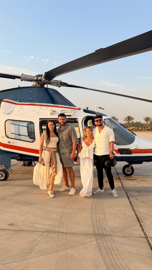 Four guests standing in front of the Xtreme Sky helicopter on the airport tarmac