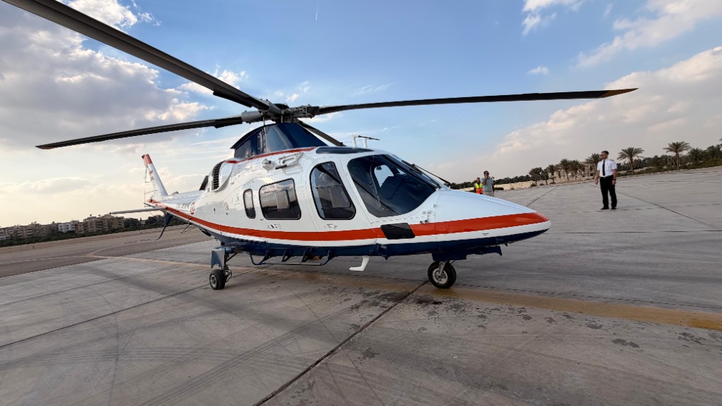 The Xtreme Sky helicopter parked on the concrete tarmac with a pilot standing nearby